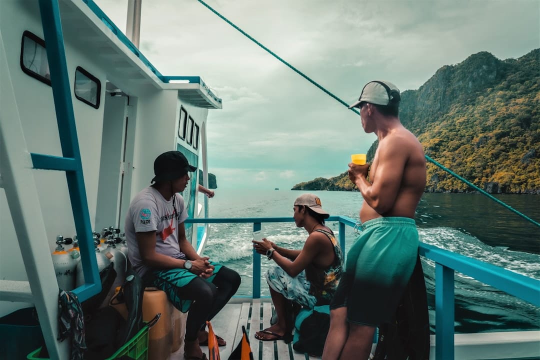 Passengers on the open deck of a boat off Palawan, dive tanks racked along the rail and a wooded island going past