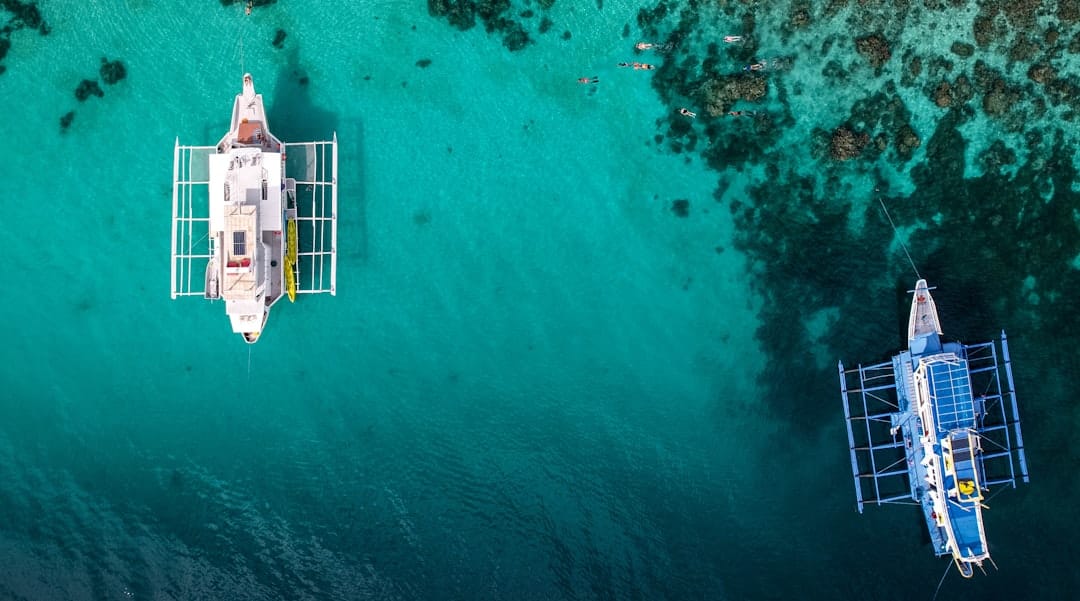 Two outrigger boats in the Philippines seen from directly above on clear turquoise water over patches of reef