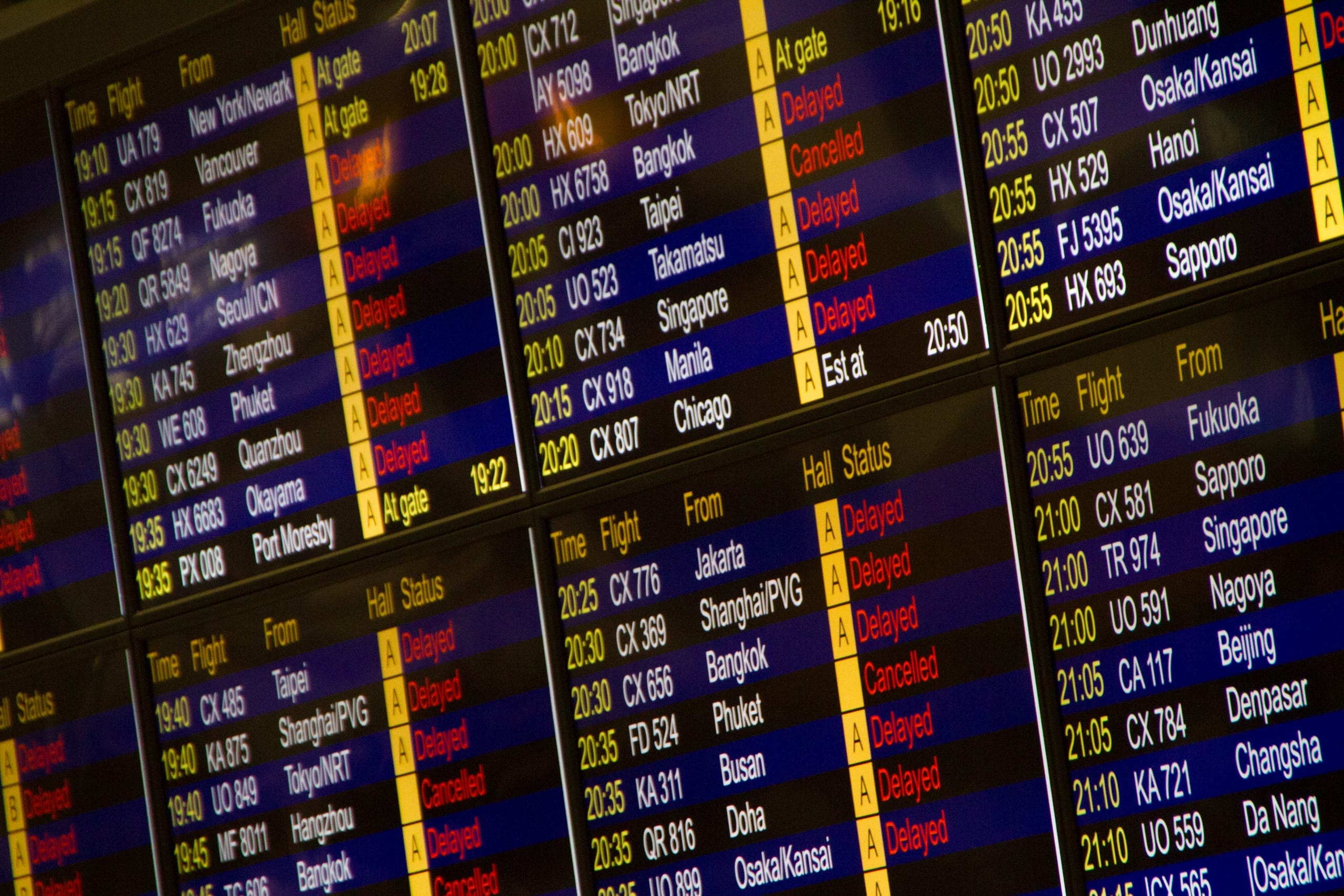 Rows of airport flight information screens listing destinations across Asia and the Americas