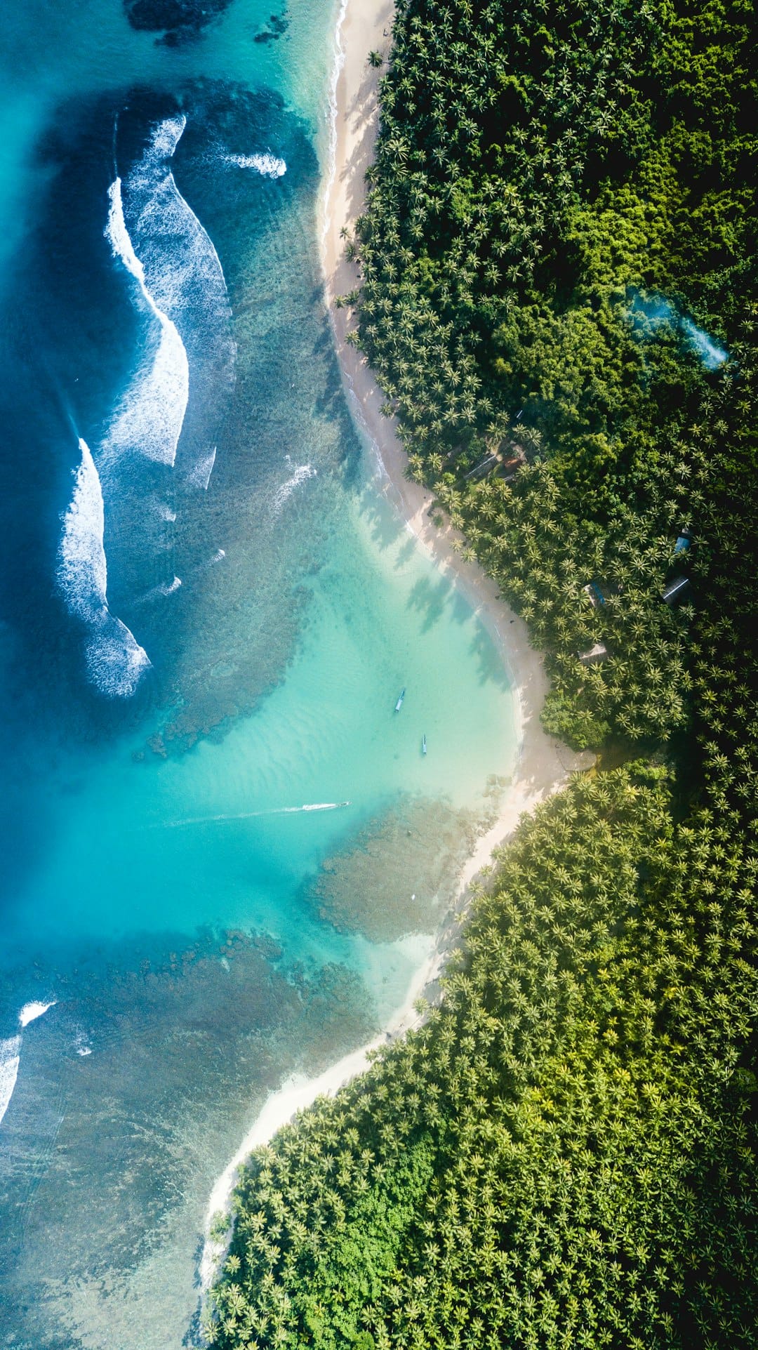 A quiet tropical bay from above, the water shading from green to deep blue