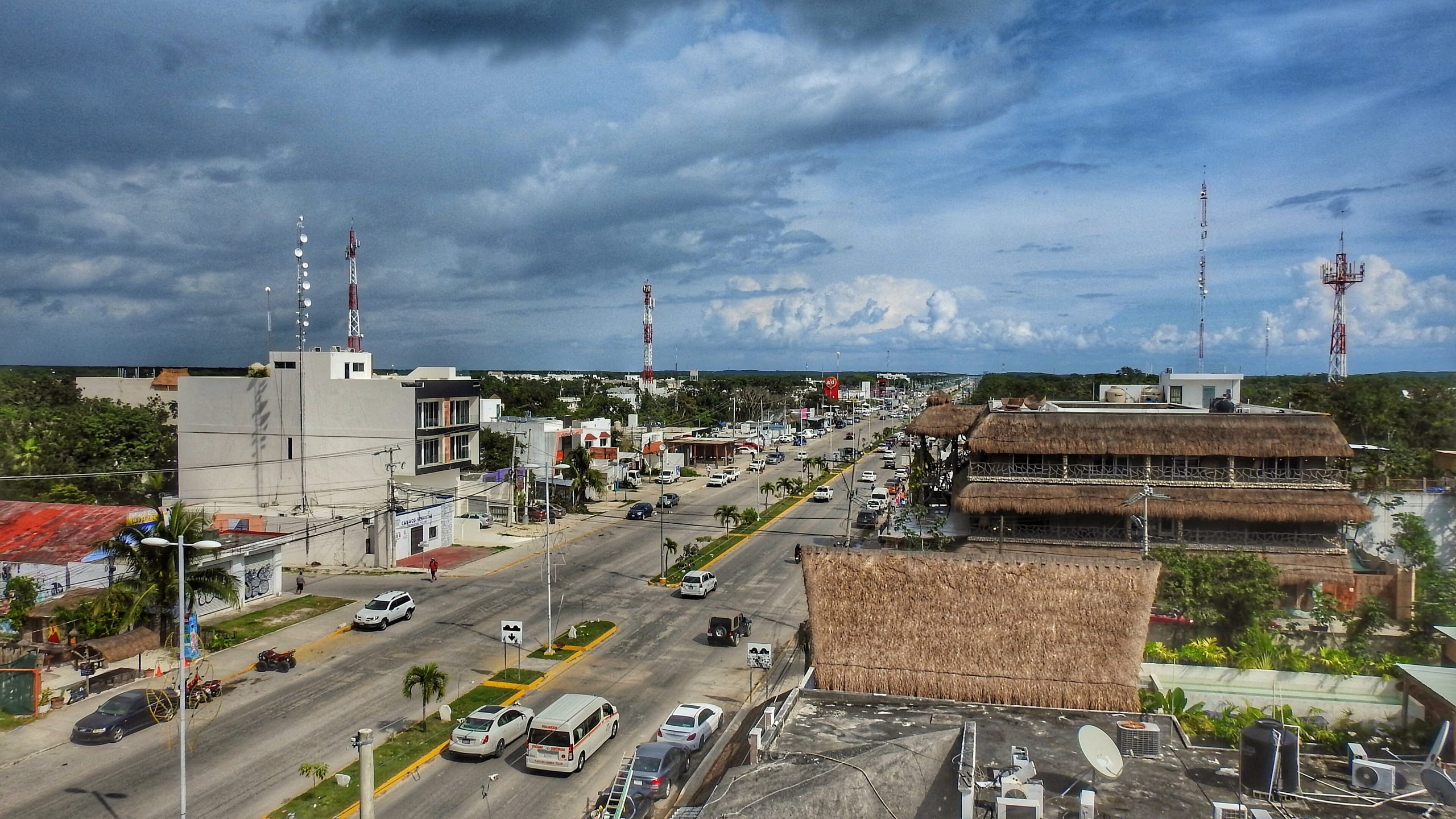 Tulum town street seen from a rooftop with a white van and thatched roofs