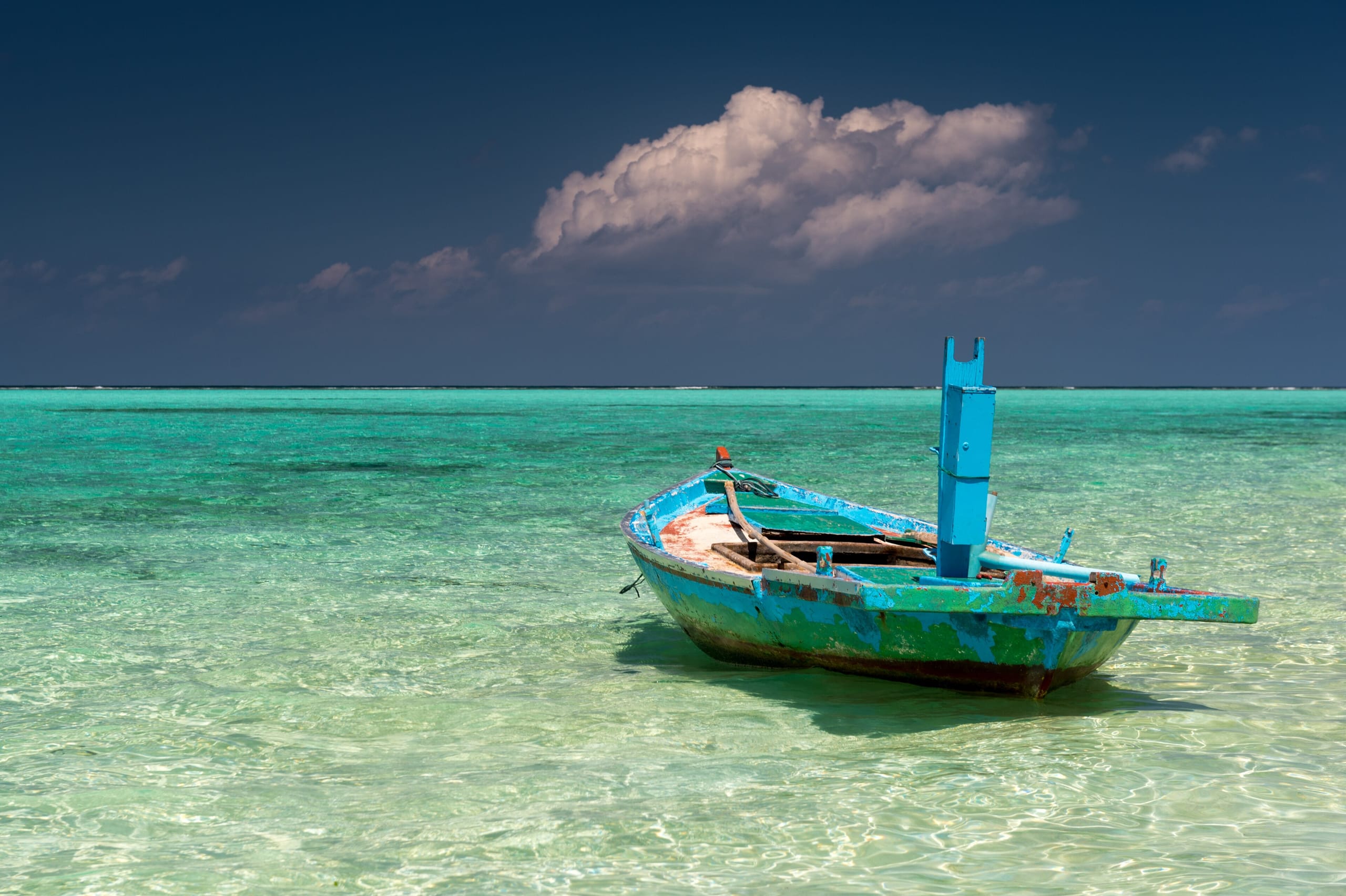 An old blue wooden boat moored in clear shallow water off Thoddoo, Alif Alif Atoll